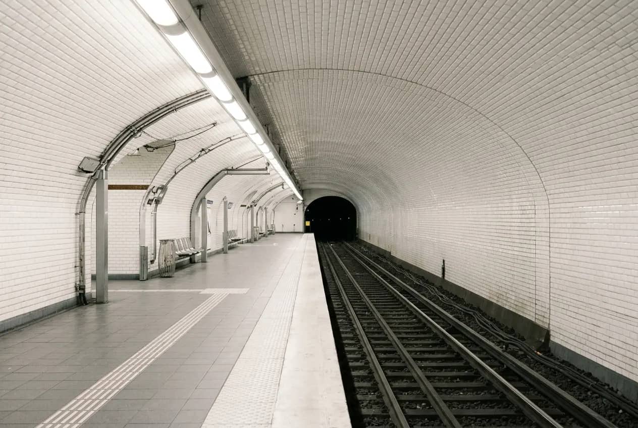Empty metro platform under a vault of white tiles, the tracks running into the tunnel